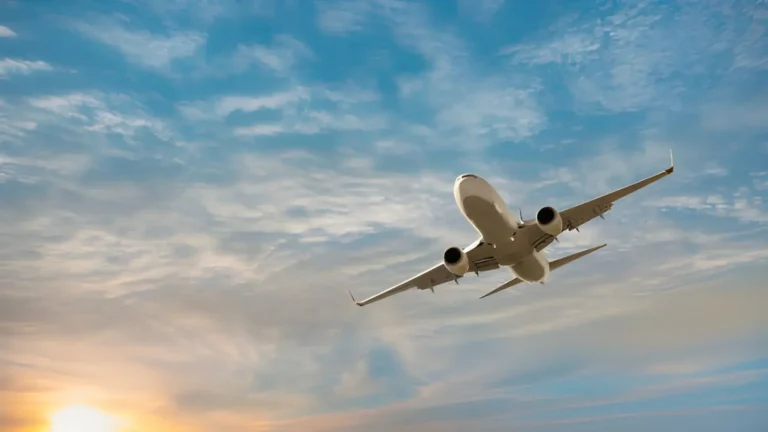 Commercial airplane taking off against a beautiful sky with soft clouds and a sunset in the background, representing air travel